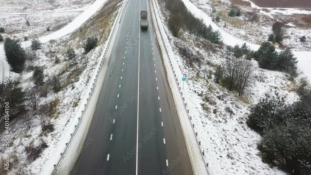 Top view of highway or road, truck and cars driving on snowy road and forest in winter time. The concept of delivery. Top view of highway or road, truck and cars driving on snowy road and forest in winter time. The concept of delivery.