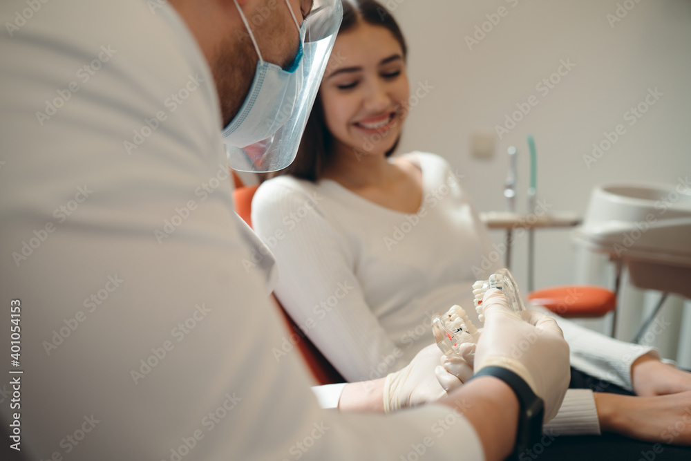 Obraz premium A specialist in white gloves tells a smiling woman an image of the oral cavity