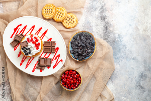 top view cake with chocolate on white oval plate bowl with cornels and raisins biscuits on beige tablecloth on marble ground with copy space photo