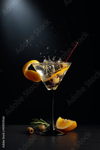 Dry martini with lemon peel and green olives on a black background. photo