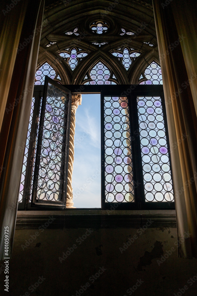 Blick aus dem Inneren des Palazzo Ducale durch die Buntglasscheiben eines gotischen Fensters in den Himmel