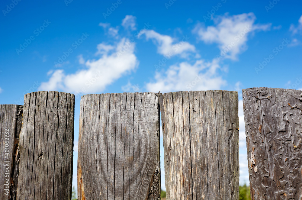 Old wooden fence against a blue sky with clouds on a sunny day Old wooden fence against a blue sky with clouds on a sunny day