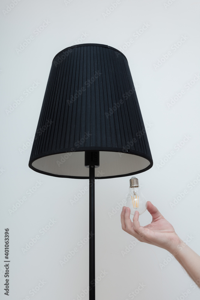 Close-up photo of A hand changes a light bulb in a stylish loft lamp Close-up photo of A hand changes a light bulb in a stylish loft lamp