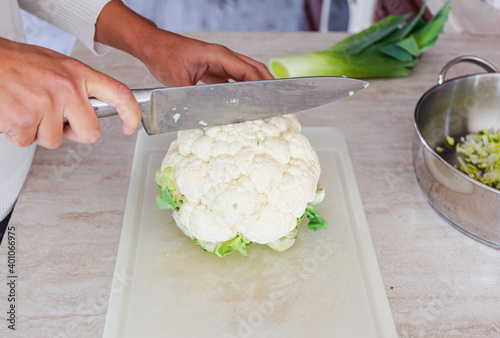 Woman cut cauliflower on cutting board on kitchen table