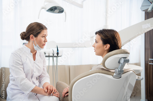 A young woman explaining her dental problem to her doctor, the doctor is listening carefuly.