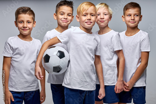 kids soccer players celebrate a winning in school sports tournament, studio portrait of happy joyful kids in uniform engaged in football