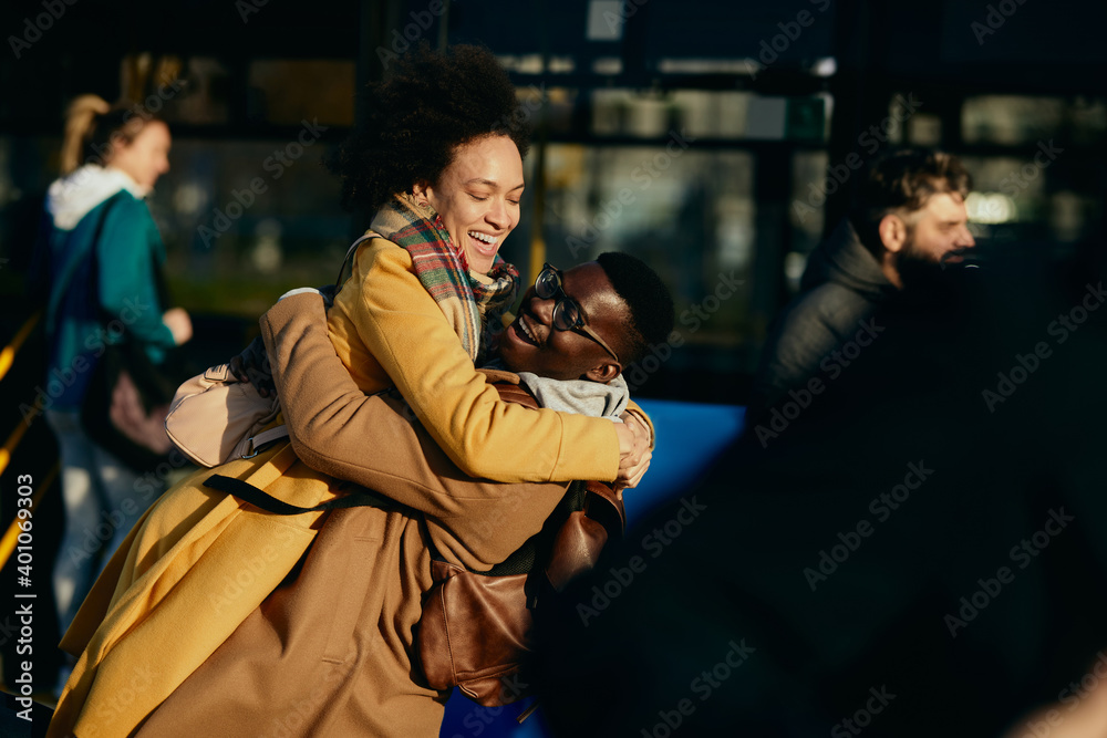 Fototapeta premium Cheerful African American couple embracing at bus station.