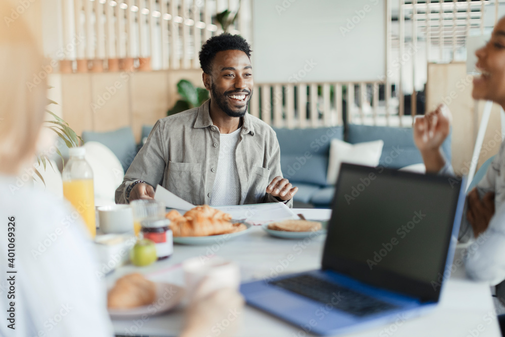 Happy businessman in meeting with coworkers at breakfast in office Happy businessman in meeting with coworkers at breakfast in office