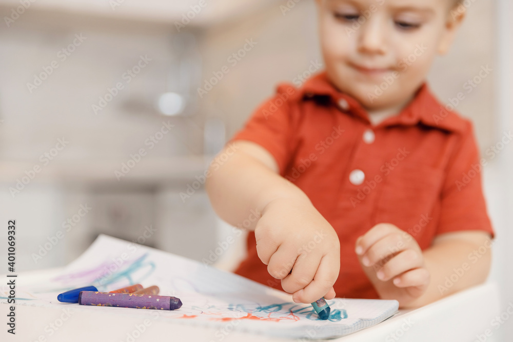 Child boy learn to draw with pencils on paper home, white kitchen background Child boy learn to draw with pencils on paper home, white kitchen background