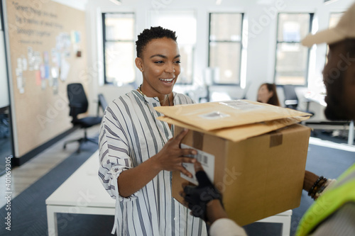 Happy businesswoman receiving packages from courier in office photo