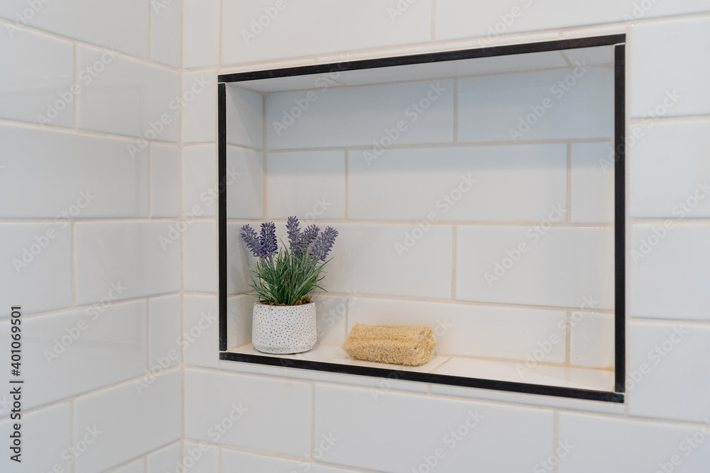 Detail of white tile shower inset with loofah and lavender plant decor. Detail of white tile shower inset with loofah and lavender plant decor.