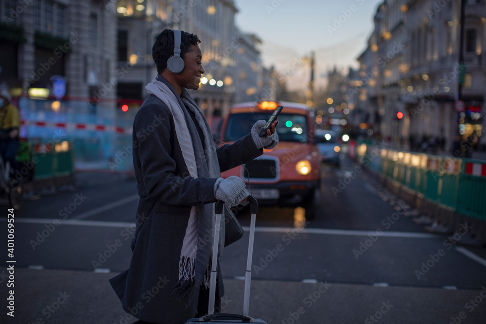 Young woman with suitcase and smart phone crossing winter city street Young woman with suitcase and smart phone crossing winter city street