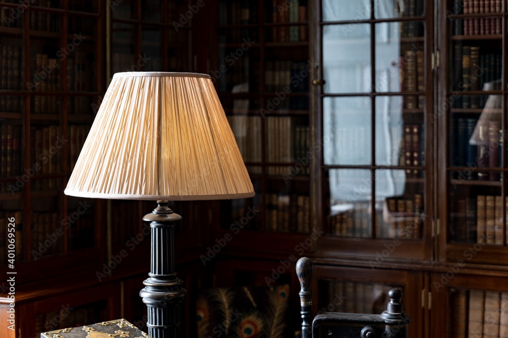 Vintage lamp on a desk in a historical library with cabinet and reflection in glass