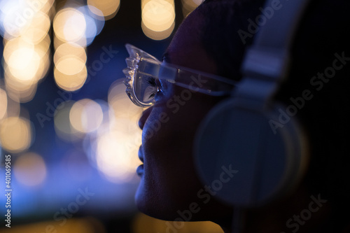 Close up young woman in funky glasses and headphones looking at lights photo