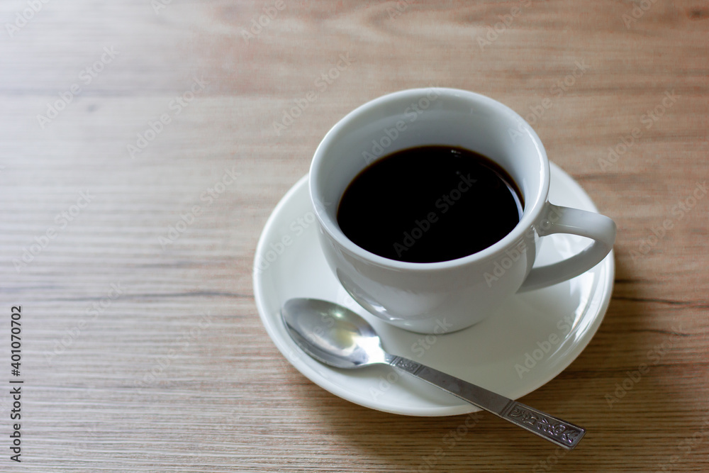 Coffee in white cup on wooden table in cafe with lighting background Coffee in white cup on wooden table in cafe with lighting background