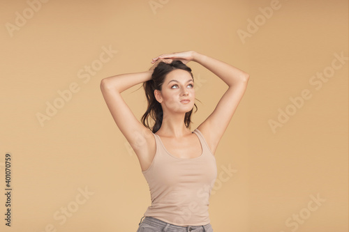 Beautiful portrait of Caucasian young brunette woman with brown eyes on beige background in studio. Skin care concept  depilation  epilation