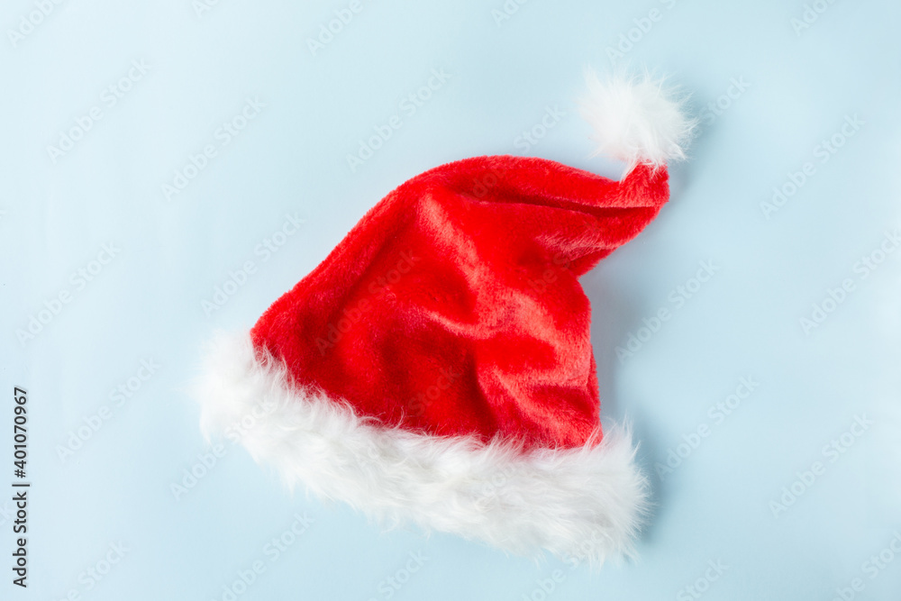 Red Santa Claus hat with white fur and bubo lies on a blue background.