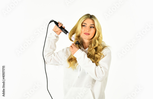Hairstyle And Hairdressing. girl curling long hair with curler. Girl care about her hairstyle. woman curling hair with straightener. woman styling her hair with a curling iron