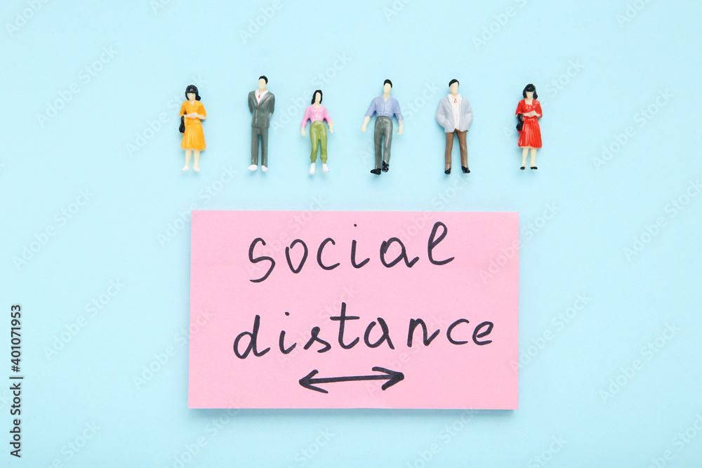 Inscription Social Distance with miniature people on blue background Inscription Social Distance with miniature people on blue background