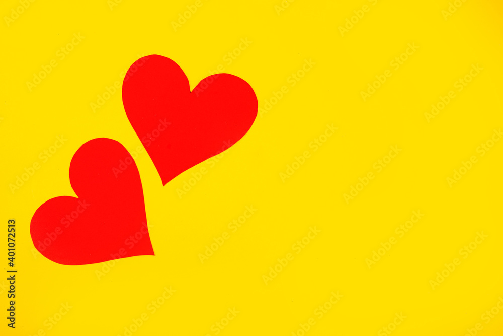 
Two red hearts representing the love of two on a yellow background for Valentine's Day, wedding and other holidays, top view.