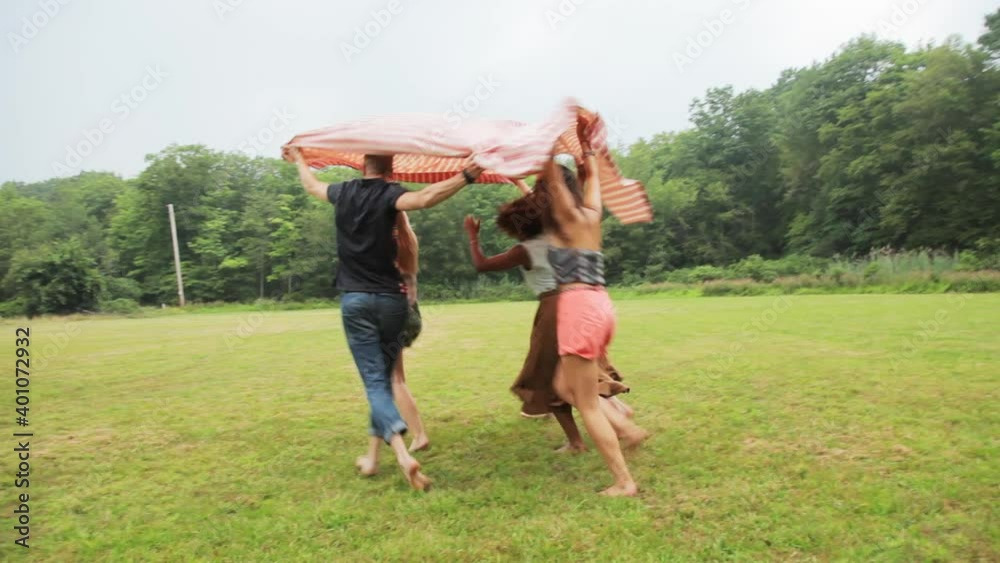 Friends running through field under blanket Friends running through field under blanket