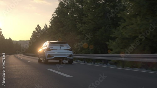 Aerial view of a self driving autonomous electric car driving along a countryside road in to the sunset. E-mobility concept. Realistic high quality 3d animation. photo
