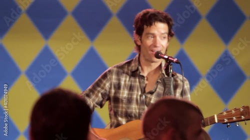 Man singing and playing guitar on stage to crowd photo