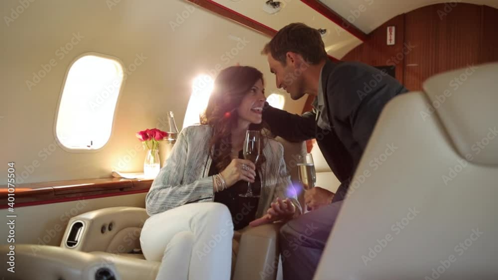 Caucasian couple drinking champagne and kissing on private jet