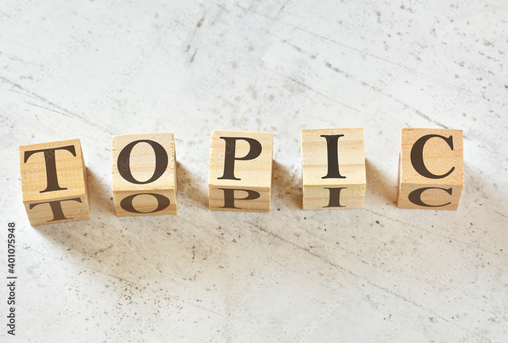 Five wooden cubes with word TOPIC on white stone like board, view from above Five wooden cubes with word TOPIC on white stone like board, view from above