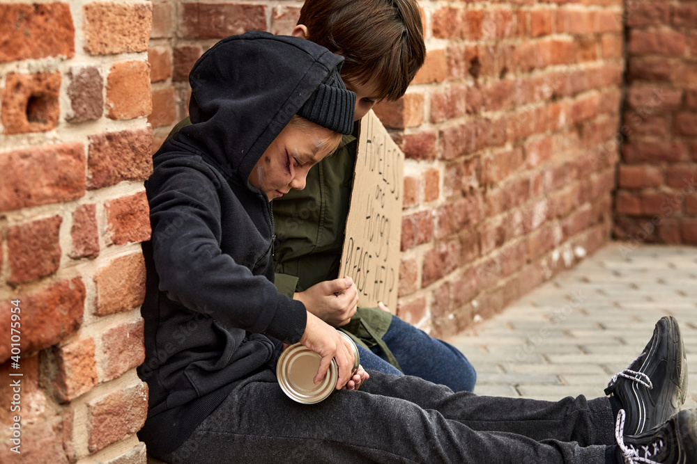 homeless kids beggars on the street with social message on the cardboard, suffer from poverty and loneliness homeless kids beggars on the street with social message on the cardboard, suffer from poverty and loneliness