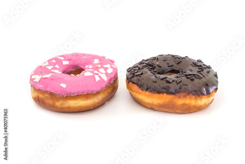 two traditional American donuts with chocolate and pink icing and sprinkles on a white plate.