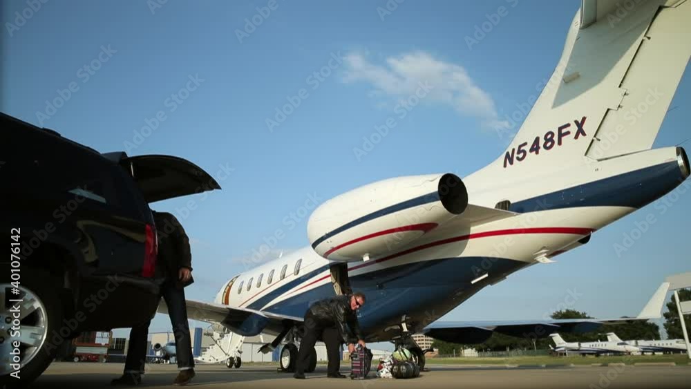 Caucasian man passing luggage to pilot near private jet