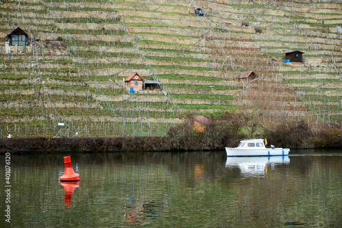 A red buoy and white boat driving by the small house in the hill on the neckar river
