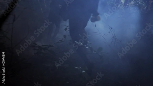 Rear view of frantic friends running in foggy woods at night photo