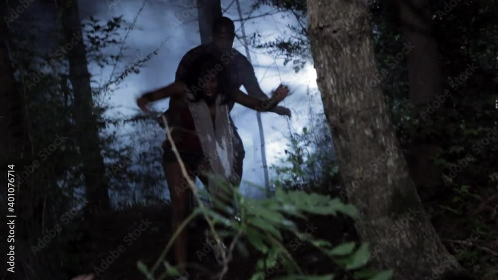 Frantic friends running down foggy hill in woods at night