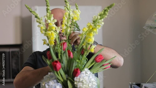 Middle-aged man arranging flowers in kitchen photo