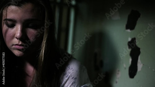 Close up of Caucasian teenage girl looking at damaged wall in jail cell