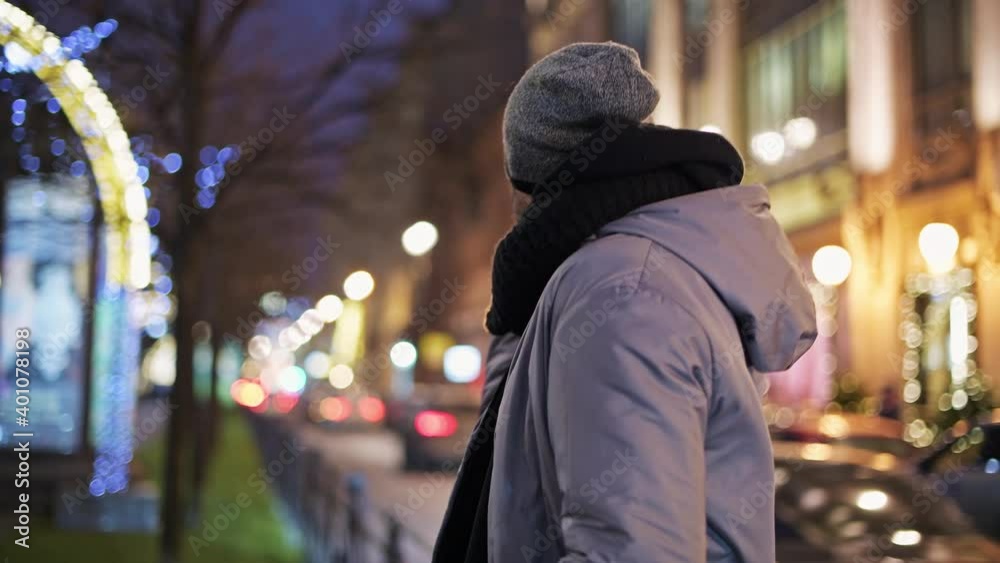 A young man communicates on the phone in the evening in the city. Big city lights. New Year's city. A young man communicates on the phone in the evening in the city. Big city lights. New Year's city.