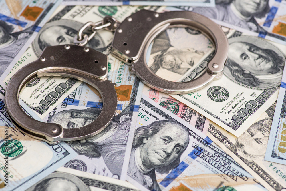 Handcuffs on money background. Dollar bills, money cash corruption, dirty money financial crime and metal police handcuffs Handcuffs on money background. Dollar bills, money cash corruption, dirty money financial crime and metal police handcuffs
