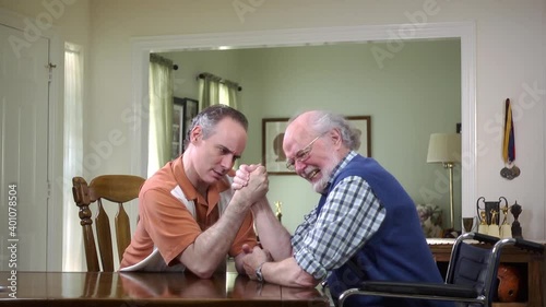 Caucasian men arm wrestling at table inside house photo