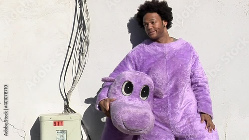 Black man in a hippo outfit relaxes on city street photo