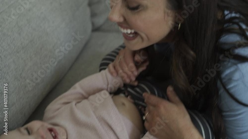 Close up of smiling mother tickling belly of baby daughter / Bluffdale, Utah, United States photo