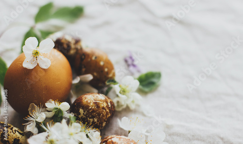Easter eggs with spring flowers on rustic linen background with space for text. Holiday aesthetic