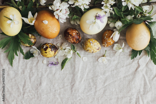Easter eggs with spring flowers on rustic linen, flat lay with space for text. Aesthetic card