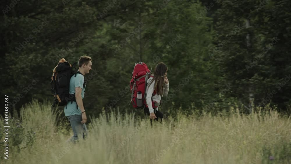 Distant teenage couple talking and hiking in field / Tibble Fork, Utah, United States