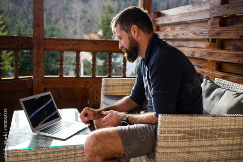 Fotografia man working on laptop in wooden cottage