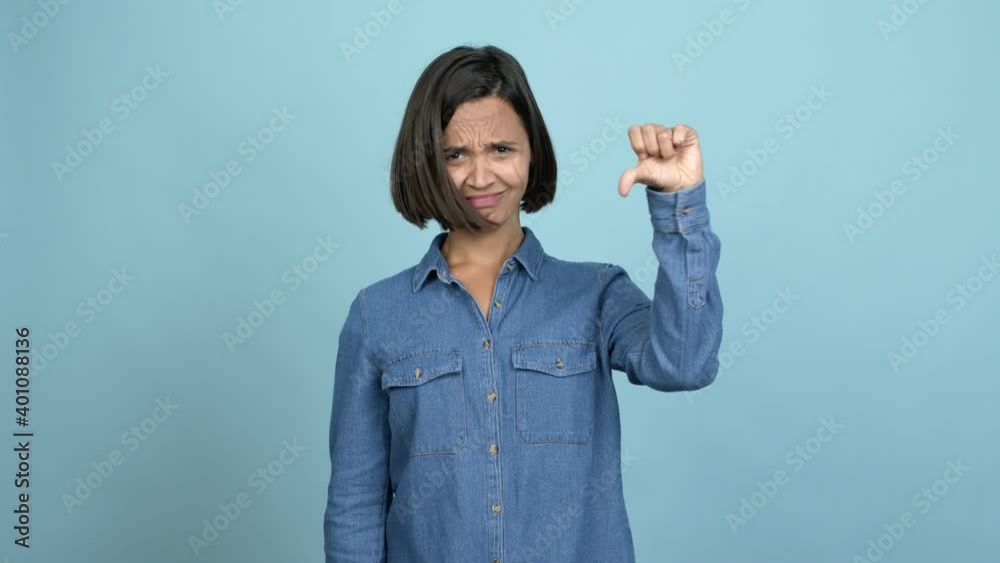 Young latin woman doing bad signal over isolated background Young latin woman doing bad signal over isolated background