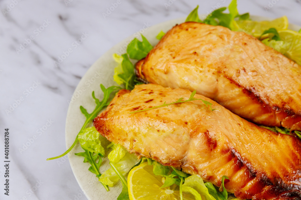 Fried salmon fillet with green salad on white plate. Fried salmon fillet with green salad on white plate.