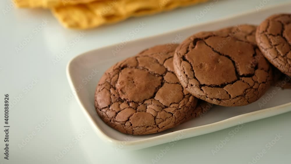 Freshly made chocolate chip cookies. Female hands put Chocolate cookies in a plate on a glass table. Closeup.