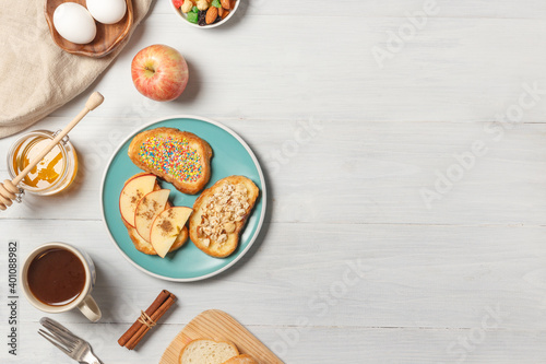 Breakfast with French toast, fruit, honey and a Cup of cocoa.Top view on light wood background with space